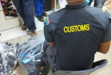 Customs official sits alongside bags of footwear during a joint operation targeting counterfeit goods in Johannesburg CBD on 13 October 2026. Photograph: SAPS.