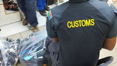 Customs official sits alongside bags of footwear during a joint operation targeting counterfeit goods in Johannesburg CBD on 13 October 2026. Photograph: SAPS.